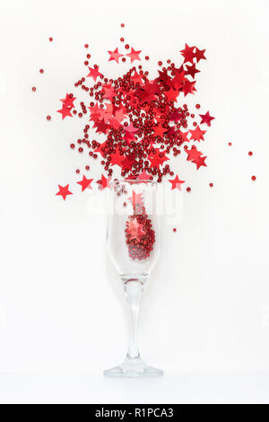 Red confetti in shape of stars poured out glasses of champagne. Top view. Christmas party. Magic night. Stock Photo