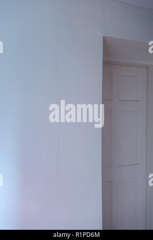 simple sheets of plain wallpaper on wall with join showing near a doorway Stock Photo