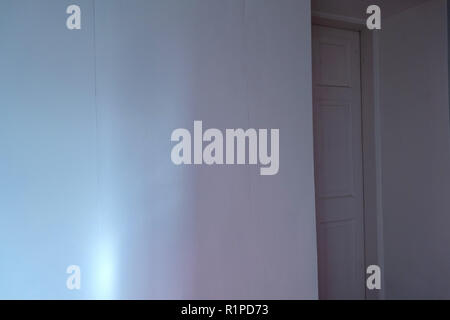 simple sheets of plain wallpaper on wall with join showing near a doorway Stock Photo