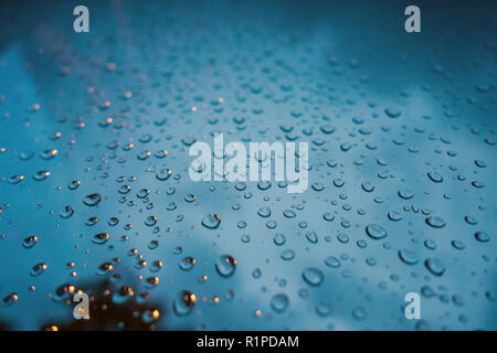 very closeup photograph of raindrops on glass window with dark sky in the background Stock Photo