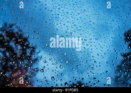 very closeup photograph of raindrops on glass window with dark sky in the background Stock Photo