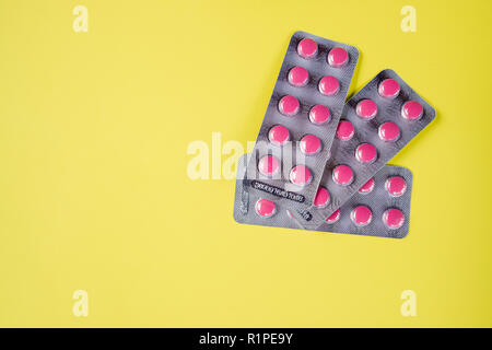 A lot of pink medicine pills.Medicine pills blister packs pile, isolated on yellow background.Pharmacy theme, Heap of pink round medicine tablet antibiotic pills.Copy space Stock Photo