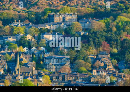 Sunny evening view over buildings (mainly residential) nestling in Wharfe Valley under moorland - Ilkley town centre, West Yorkshire, England, UK. Stock Photo