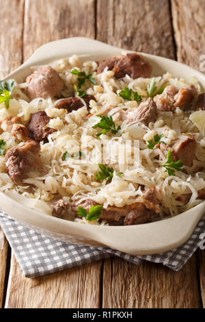Delicious traditional Estonian mulgikapsas  stewed pork with sauerkraut and barley close-up in a pan on the table. vertical Stock Photo
