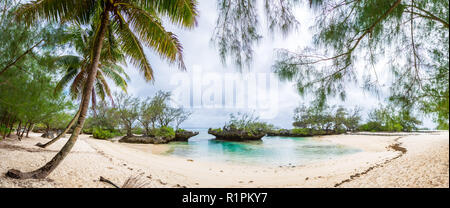 View of yellow white sandy tropical beach under palm trees in a secluded bay with coral rocks. Rimatara island, Austral islands, French Polynesia. Stock Photo