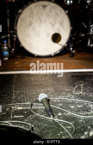 Microphone on empty stage with out of focus background elements Stock Photo