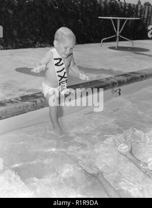 A baby with a Nixon sash is poolside, ca. 1960. Stock Photo