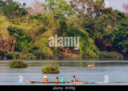 Don Det, Laos - April 22, 2018: Local people navigating the Mekong river on a boat surrounded by forest near the Cambodian border Stock Photo