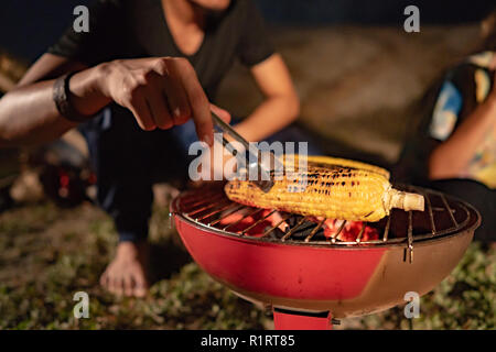 group of friends having fun camping, making roasted corn and enjoy the camp fire Stock Photo
