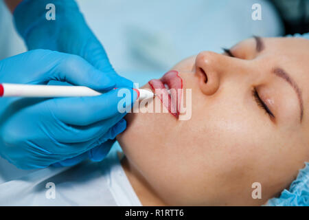 Cosmetologist, marks the pencils on the lips for permanent lip makeup Stock Photo