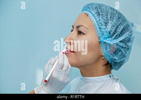 Cosmetologist, marks the pencils on the lips for permanent lip makeup Stock Photo