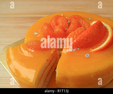 Sweet and sour mandarin orange cake with one piece cut from the whole cake Stock Photo
