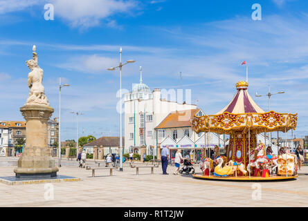 Lowestoft fairground carousel and Tritin statue near Royal Norfolk and Suffolk Yacht Club Royal Plain seafront Lowestoft Suffolk England UK GB Europe Stock Photo