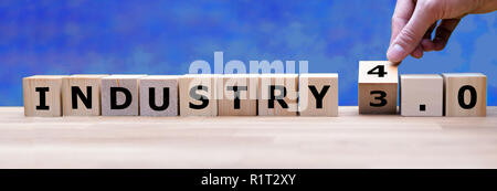 Hand is turning a dice and changes the word "Industry 3.0" to "Industry 4.0" Stock Photo