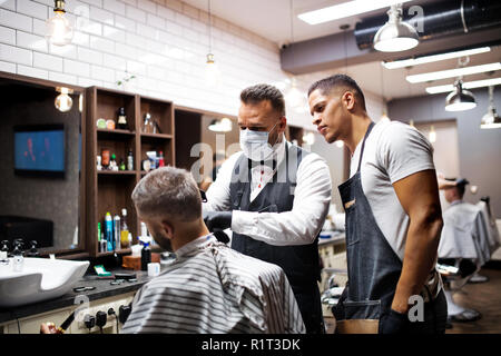 Hipster man client visiting haidresser and hairstylist in barber shop, training concept. Stock Photo