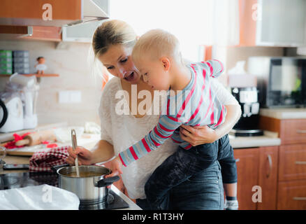A handicapped down syndrome boy cooking soup with his mother indoors. Stock Photo