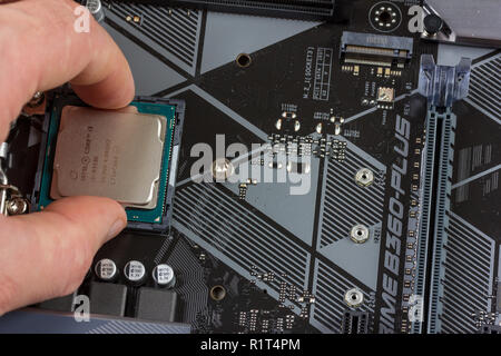 Maykop, Russia - November 9, 2018: man installs an 8th generation Intel core I3 processor into a motherboard socket Stock Photo