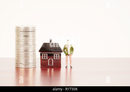 Miniature figure,stack of coins and metal house replica for property investment concept Stock Photo