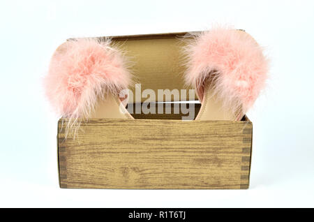 Pink feather slippers in a cardboard box with wooden pattern Stock Photo
