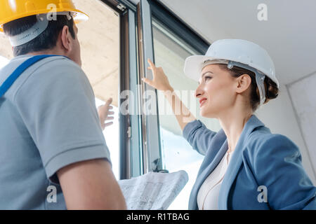 Architect woman and construction worker checking windows on site Stock Photo