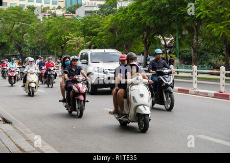 Street scene with people riding motorbikes and scooters on a busy city road. Hanoi, Vietnam, Asia Stock Photo