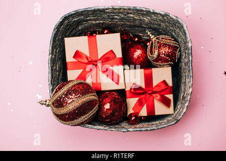 Silver box with presents and red christmas balls on pink pastel background. Flat lay. New year concept.