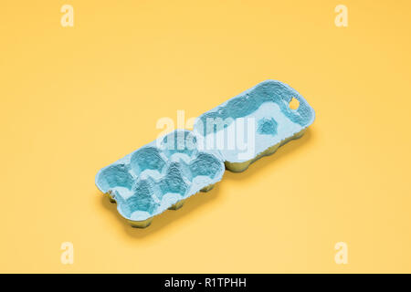 Half dozen egg carton empty on yellow.  Six egg crate container empty and open on a bright pastel yellow background with copy space and room for text Stock Photo