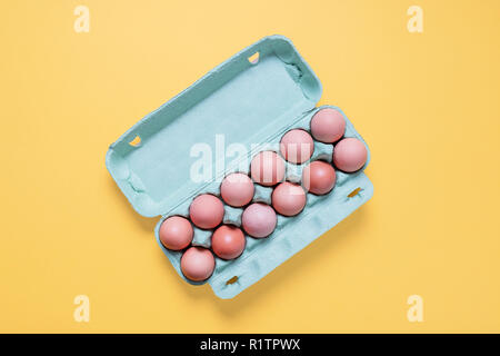 Top view of dozen free range brown eggs in carton.  Twelve brown eggs in crate container on a bright pastel yellow background Stock Photo