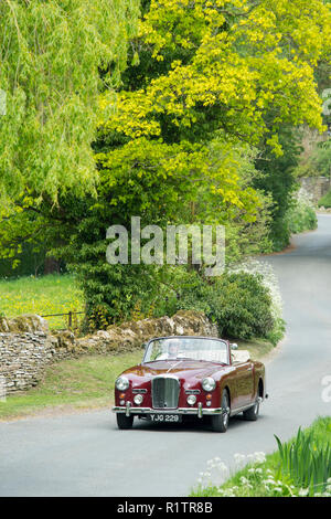 Motorist driving 1961 British made Alvis TD21 DHC Series 1 drophead ooupe classic car on country lane in The Cotswolds, England Stock Photo