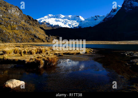 Beautiful of the Carhuacocha lagoon in front of the snow-covered cochas in the Huaytapallana mountain range during the dawn. Stock Photo