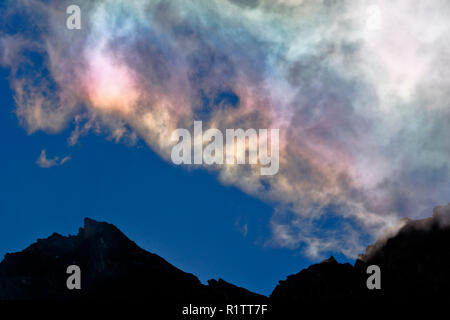 A natural phenomenon called iridescent clouds, in this case recorded in the morning with the light of the sun emerging from the rocks in the high Ande Stock Photo
