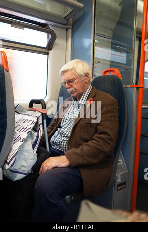 Senior man resting on his train journey on a London Overland Train Stock Photo