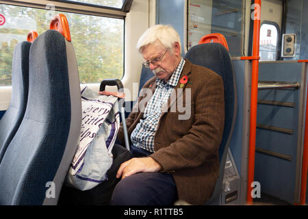 Senior man resting on his train journey on a London Overland Train Stock Photo