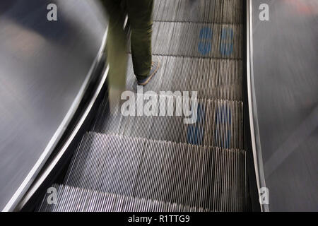 Tube commuters time, closeup blurred feet of commuter travelling down on the Underground escalators to the London tube train Stock Photo