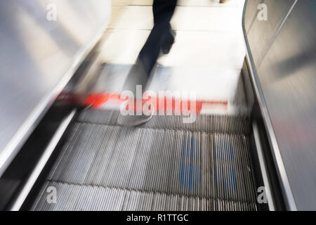 Tube commuters time, closeup blurred feet of commuter travelling up on the Underground escalators from the London tube train Stock Photo