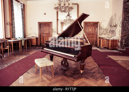 Bad Gastein, Austria - March 15, 2015: Old piano and furniture in room at the abandoned Hotel Straubinger. Stock Photo