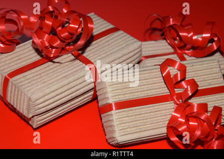 birthday or christmas present boxes, top view of gift box wrapped in cardboard packaging with red ribbon on red surface Stock Photo