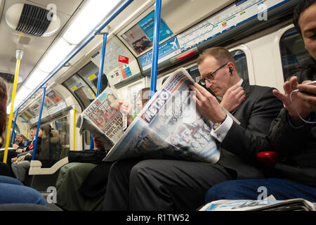 Tube commuters time, commuters reading and using smartphones and  london newspaper on the London Underground Tube Stock Photo