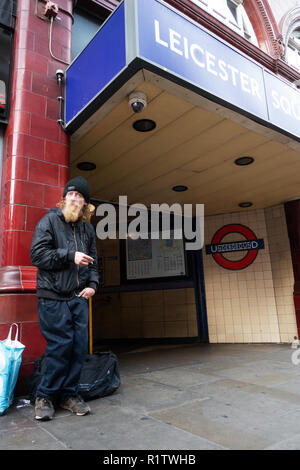 Homeless man standing on the street outside Leicester Square Tube Station Stock Photo