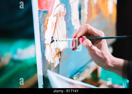 Woman paints a painting on canvas. Art academy or drawing school. Girl paints on the easel. Only hand of unknown artist, brush and canvas Stock Photo
