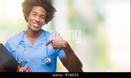 Afro american surgeon doctor holding clipboard man over isolated background with surprise face pointing finger to himself Stock Photo