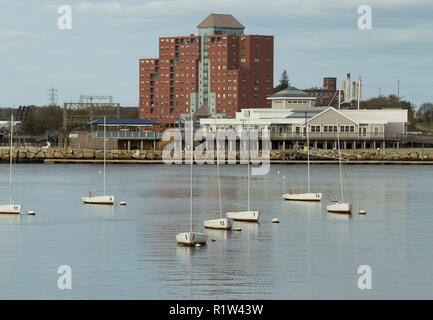 Small skiffs in Taunton River with high rise red brick building in background, Fall River, Massachusetts. Located next to Battleship Cove and park. Stock Photo