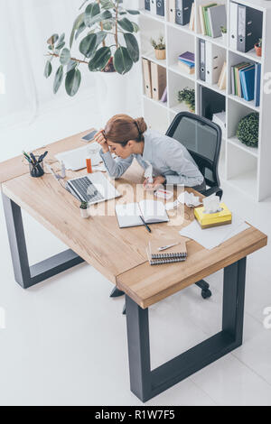 high angle view of sad sick businesswoman sitting at workplace with various medicines Stock Photo