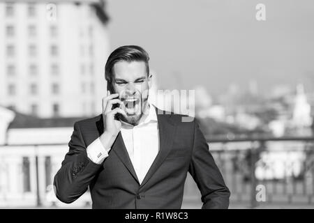 Happy manager talk on smartphone. Man with mobile phone on sunny terrace. Businessman in blue suit outdoor. Business communication, new technology and sms. Modern life and business lifestyle. Stock Photo