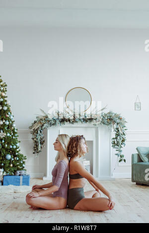 view of two girl sitting in lotus position and doing yoga at home Stock Photo