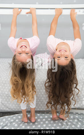 Little girls with long blond hair hang upside down. Hair salon for kids. Stock Photo