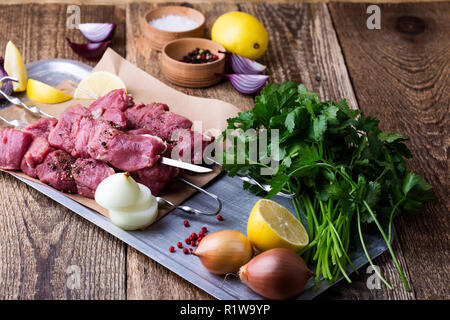 Raw fresh beef skewers,butchery uncooked chopped meat and cooking ingredients on wooden table Stock Photo