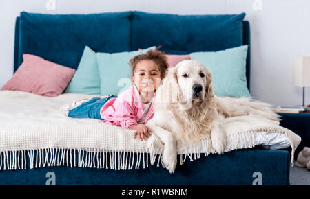Girl lying on a bed with her golden retriever dog Stock Photo - Alamy