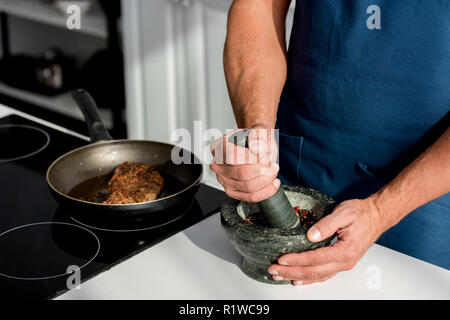 partial view of male hands crushing spices on kitchen table Stock Photo