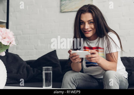 smiling young transgender man using smartphone on couch at home Stock Photo